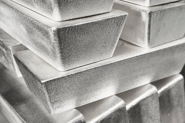 Stack of shiny industrial silver metal ingots at bright light in jewelry storage of manufacturing plant extreme close view